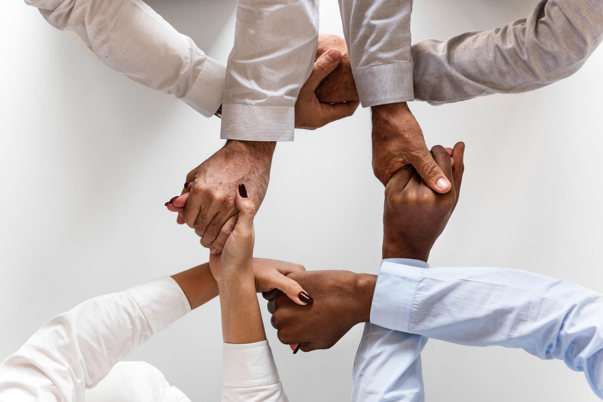 Hands of several people from different backgrounds clasped together in a linked circle