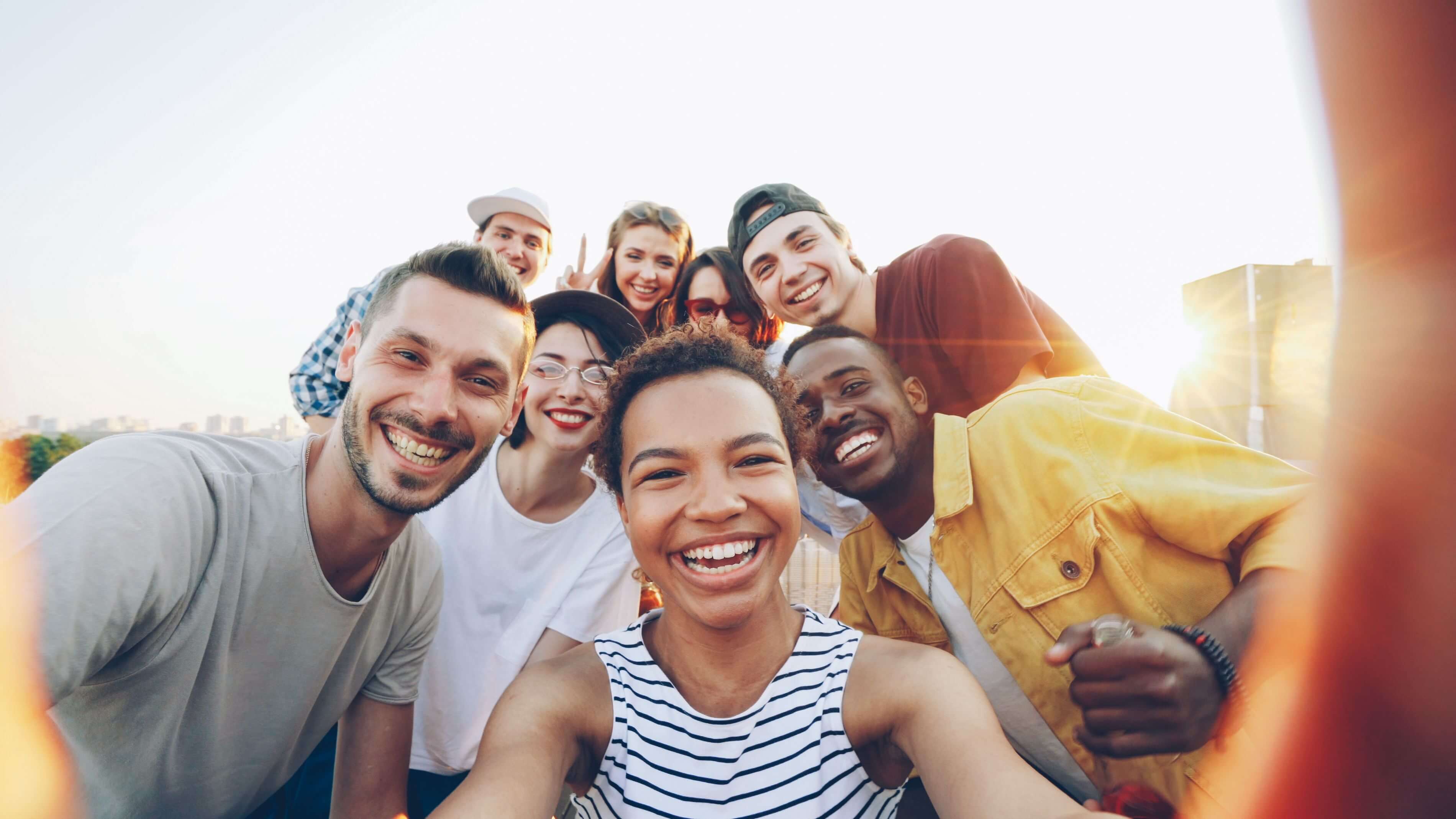A group of smiling friends taking a selfie together outdoors