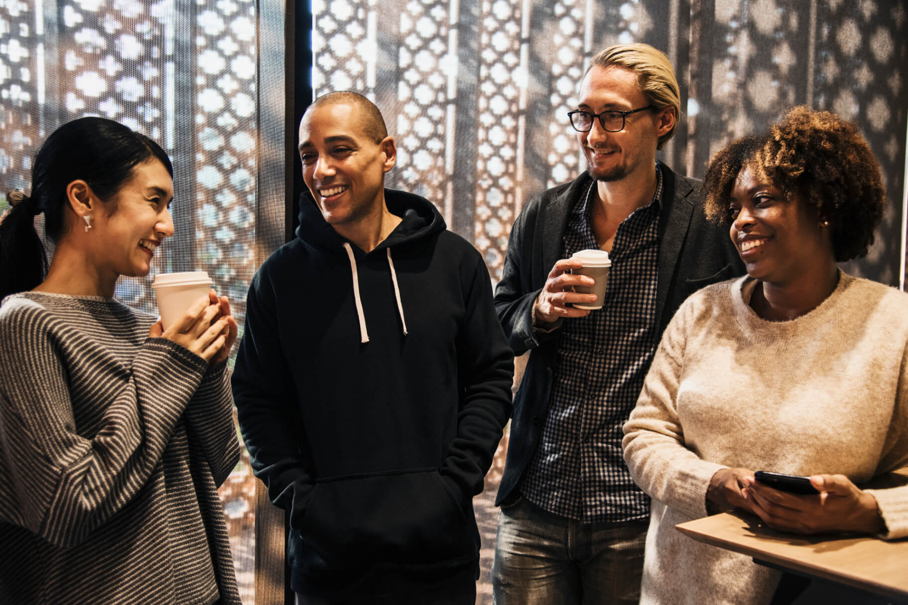 Four friends laughing together over coffee